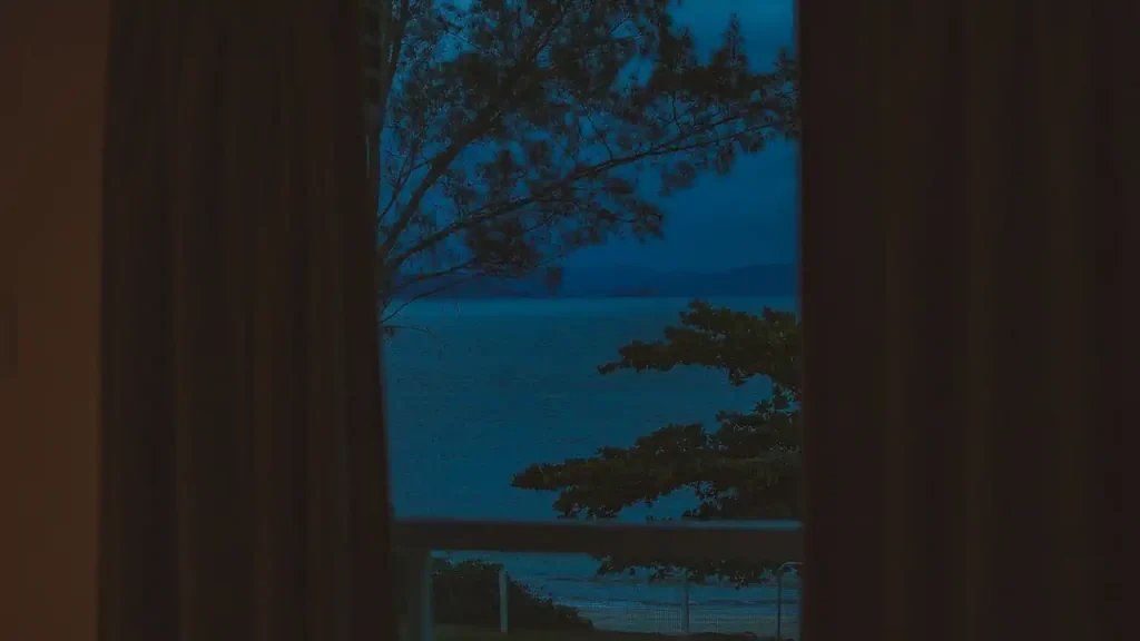 Vista noturna de uma varanda que dá para o mar.